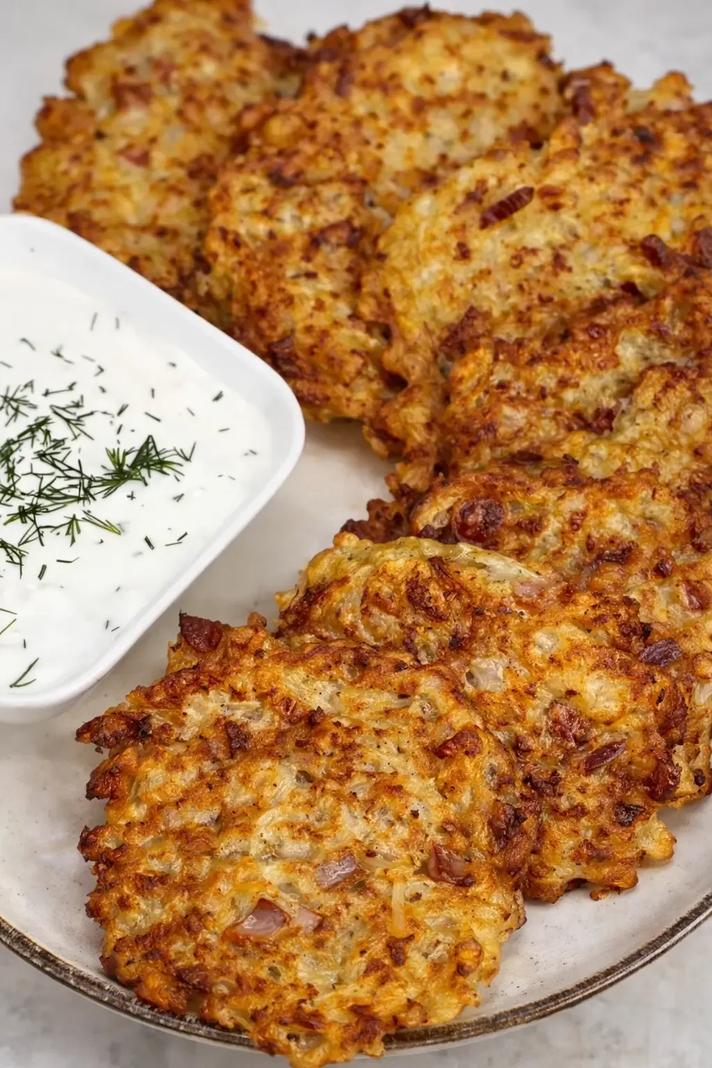 Złociste placki z kapusty kiszonej z kiełbasą i serem ułożone na talerzu 